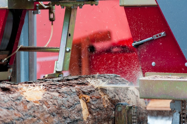製材所。機器製材所で丸太を機械加工するプロセス機械のこぎりは、板板上の木の幹を見ました。
