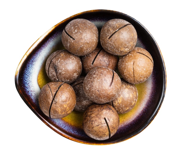 Sawn macadamia nuts in ceramic bowl isolated