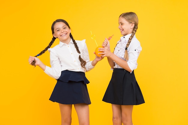 健康に「はい」と言う 黄色の背景に健康のためにオレンジ色の果物のジュースを飲む小さな学童 子供の健康のための栄養 ジュースを飲むと健康を増進できます