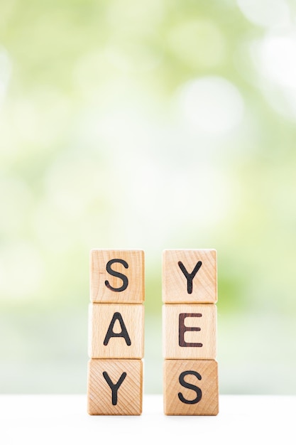 SAY YES word is written on wooden cubes on a green summer background Closeup of wooden elements