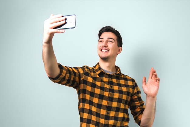 Saying hello. handsome man in square shirt waving on video chatting