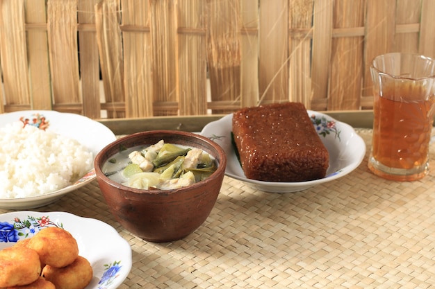 SayurLodehまたは野菜とココナッツミルクのスープ。竹のテーブルで提供される伝統的なボウルのジャワからの伝統的なインドネシア料理。セレクティブフォーカス