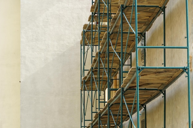 Scaffolding is installed along the wall of the building under construction plastering and painting of the facade of the house metal supports and wooden platforms for working at height