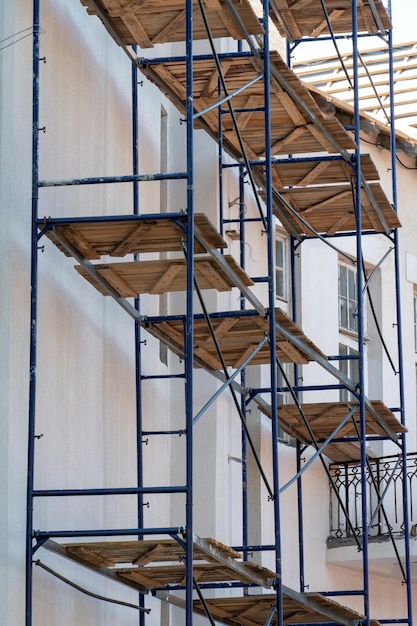 Scaffolding made of metal profile and wooden decking along the\
building during the renovation restoration of an old building in\
the historical center of the city repair of the roof and\
facade