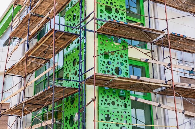 Scaffolding with wooden decks. performing construction work at\
height. sheathing of the ventilated facade with metal.