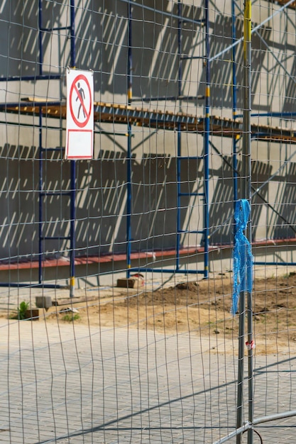 Scaffolding wordt langs de muur van het gebouw in aanbouw geïnstalleerd Gips en schilderen van de gevel van het huis Metalen steunstukken en houten platforms voor werk op hoogte