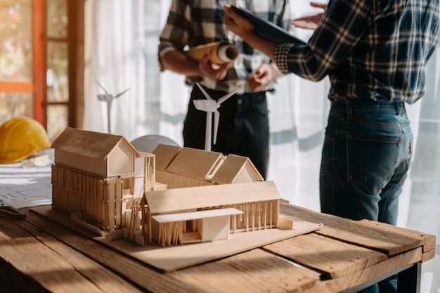 Scale model house on table with architects two architects
making architectural model in office together to form a new
buildin