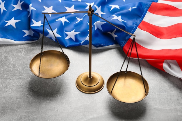 Photo scales of justice and american flag on light grey table