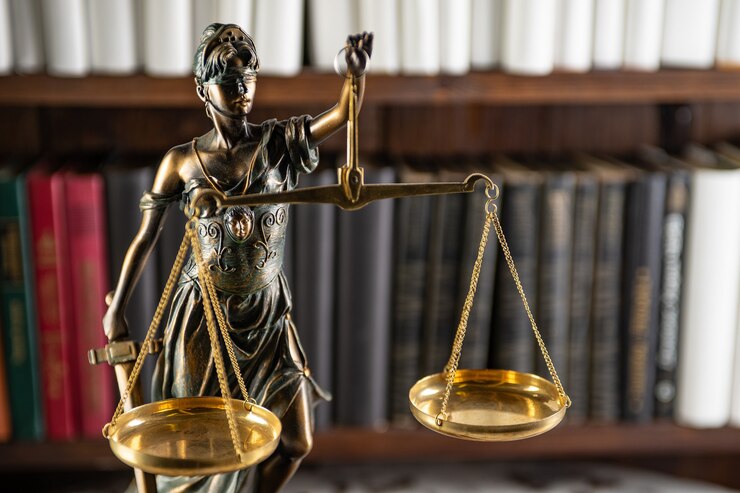 Photo scales of justice, lady justice, law library concept, law books in the background.