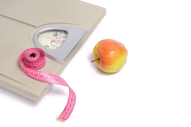 Scales with measuring tape and apple, symbol and concept weight loss, sports and fitness.