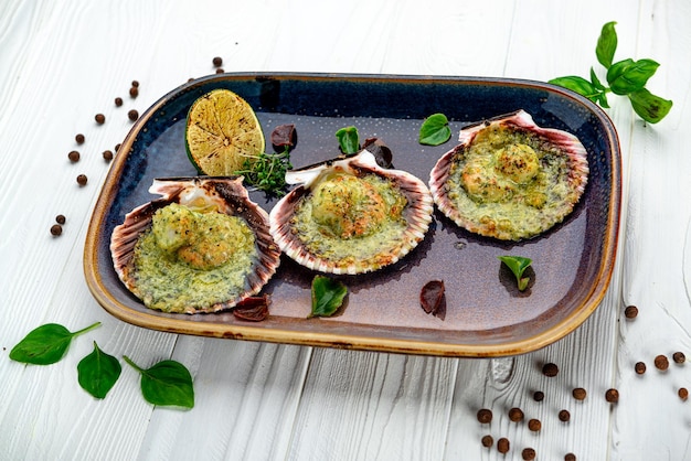 Scallops baked in a shell with cheese and pesto sauce