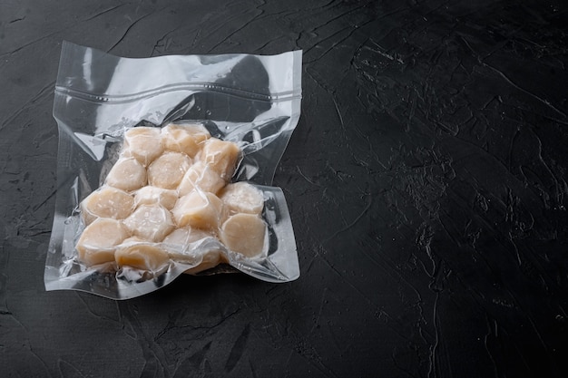 Scallops, in vacuum pack, on black textured table with copy space