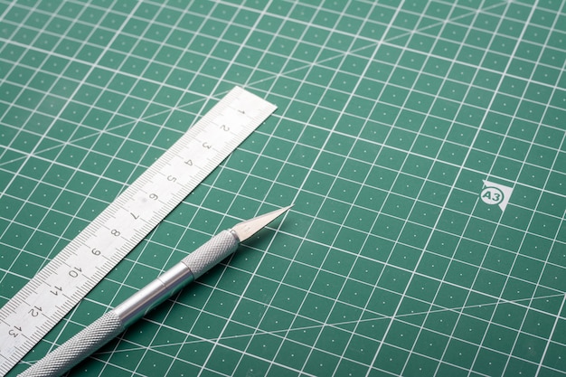 Scalpel for cutting paper and ruler on cutting mat background