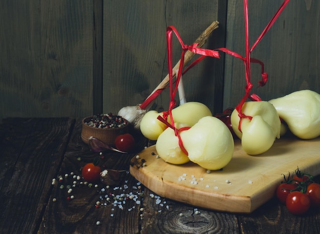 Scamorza 치즈이탈리아 카시오카발로 치즈와 붉은 토마토는 오래된 나무 탁자에 있는 소박한 배경입니다.