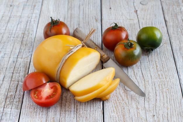 Scamorza with tomatoes and knife on a wooden table