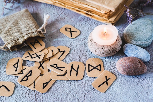 사진 스칸디나비아의 고대 룬은 행운을 말하고 가방에 불과 테이블에 돌을 놓습니다.