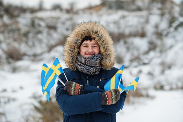 Scandinavian man with Sweden flag in winter swedish landscape