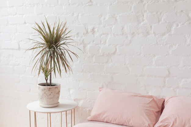 Скандинавский минималистичный интерьер спальни. Белая кирпичная стена фон. Розовое постельное белье.