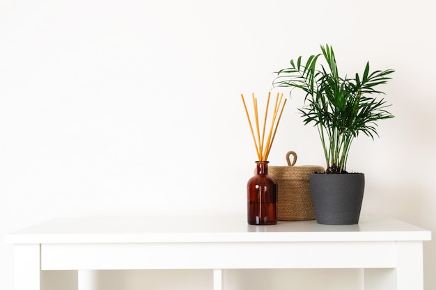 Scandinavian nordic hygge style, home interior  evergreen plant, scent aroma diffuser, small straw basket, white shelf