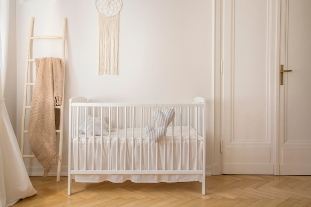 Scandinavian nursery with white wooden crib and macrame on the wall in tenement house real photo with copy space