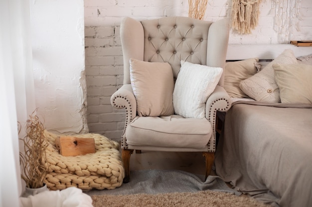 Скандинавский дизайн стильного интерьера комнаты с удобным серым креслом и подушками.