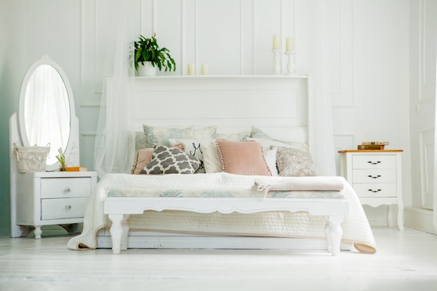 Scandinavian style white bedroom. Four pillows are on the bed. Modern interior