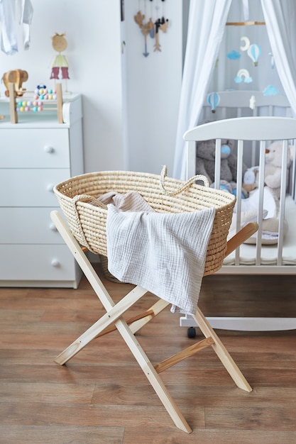 Scandinavian style white interior children's room, bedroom, nursery. Baby cot with Ã¢ÂÂcanopy. Wooden shelves and toys. Wicker cradle with legs