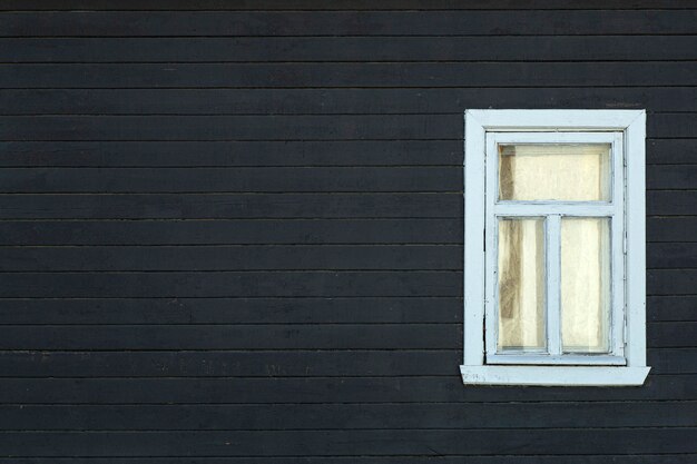 Scandinavisch huis. donkere houten muur van de gevel van een scandinavische huis met een raam.