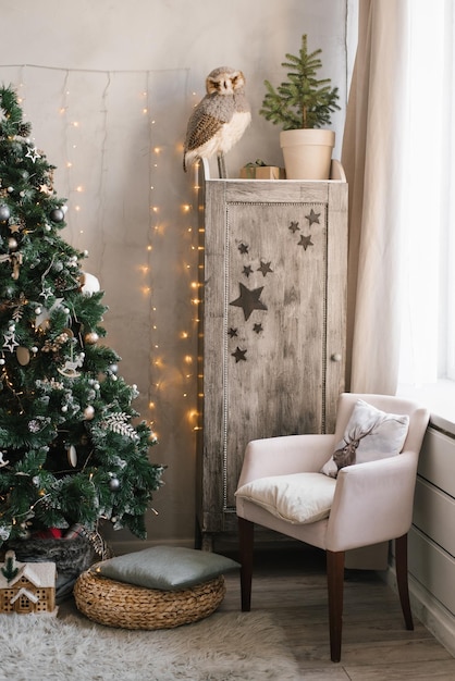 Scandinavisch kerstinterieur versierd met een kerstboom in de kinderkamer Kledingkast met kinderspeelgoed fauteuil