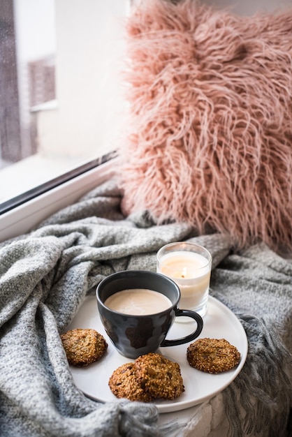 Scandinavisch ontbijt kopje koffie en koekjes op gezellige vensterbank met warme deken