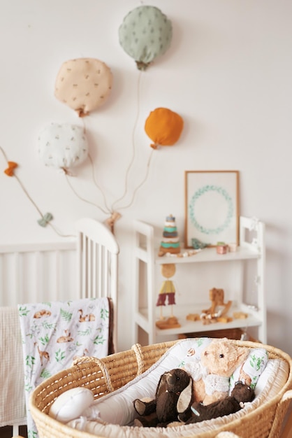 Scandinavische stijl wit interieur kinderkamer, slaapkamer, kinderkamer. Babybedje met luifel. Houten planken en speelgoed. Rieten wieg met poten. Textiel vlieger en ballonnen.