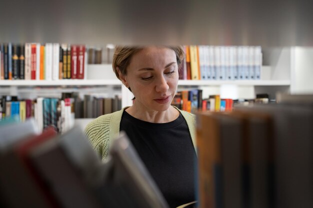 Scandinavische vrouw van middelbare leeftijd die een leerboek kiest op zoek naar literatuur tijdens de voorbereiding op een examen