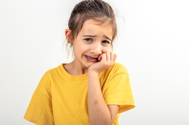 Scared and anxious girl biting her fingernails on a white background isolated