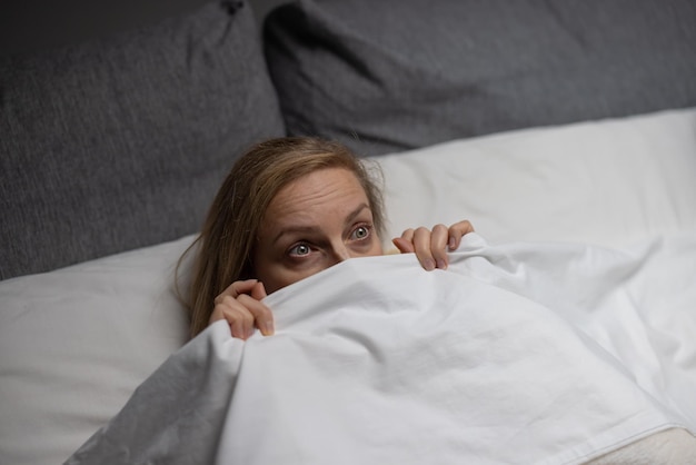 Scared caucasian woman lying on comfy