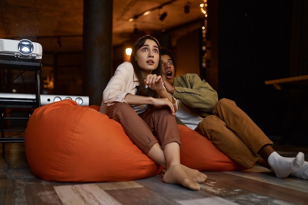 Scared couple watching horror movie at home