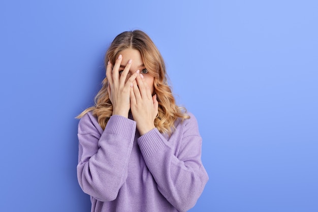 Scared female covering her face with hands