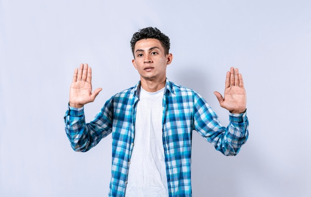 Scared and horrified man with raised palms Man with a frightened face with his hands raised in front Portrait of scared person with raised hands Scared guy with raised hands in front