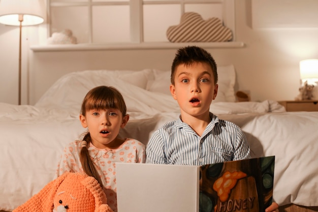 Bambini piccoli spaventati che leggono la favola della buonanotte a casa