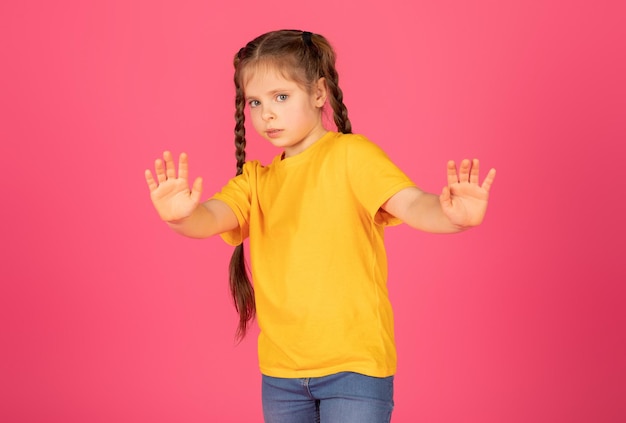 Scared little girl showing stop gesture with hands and looking at camera