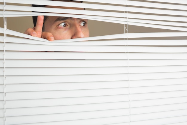 Scared male eyes spying through roller blind