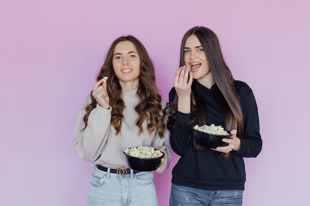 Испуганные шокированные молодые женщины, подруги, смотрящие фильм, держат ведро попкорна