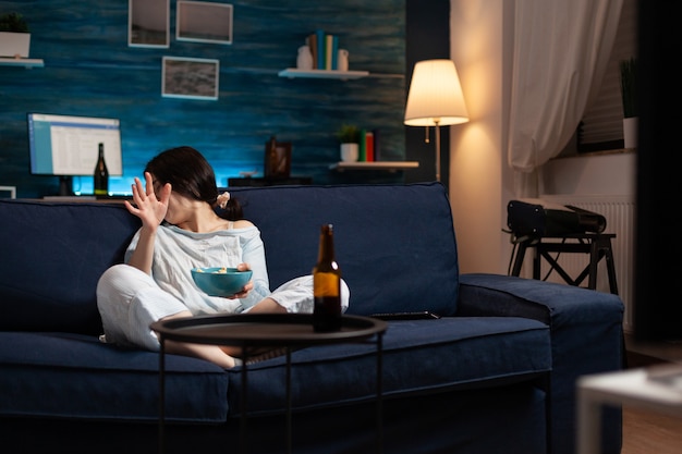 Scared terrified woman watching horror film on television eating popcorn