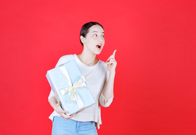 Scared woman holding wrapped gift box and looking away