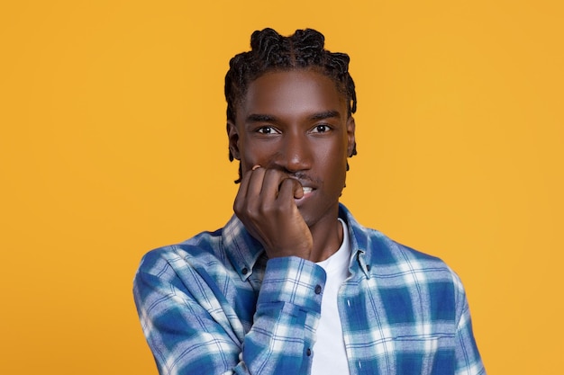 Scared young black man biting his nails and looking at camera