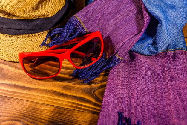 Scarf straw hat and eyeglasses on wooden table