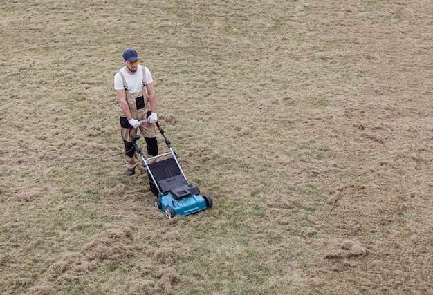 スカリファイヤーで芝生を怖がらせる。男の庭師は芝生と古い草の除去を怖がらせます