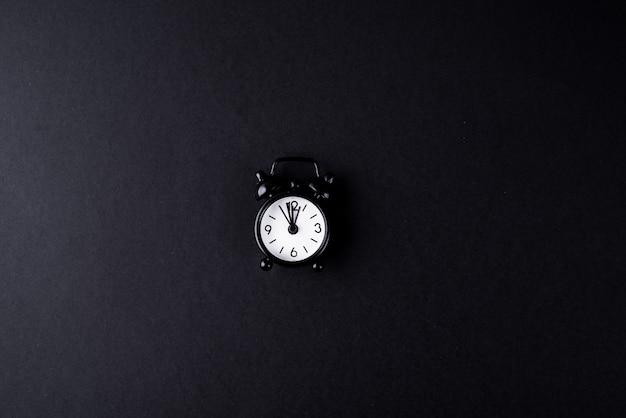 Scarlet black alarm clock on a black background.