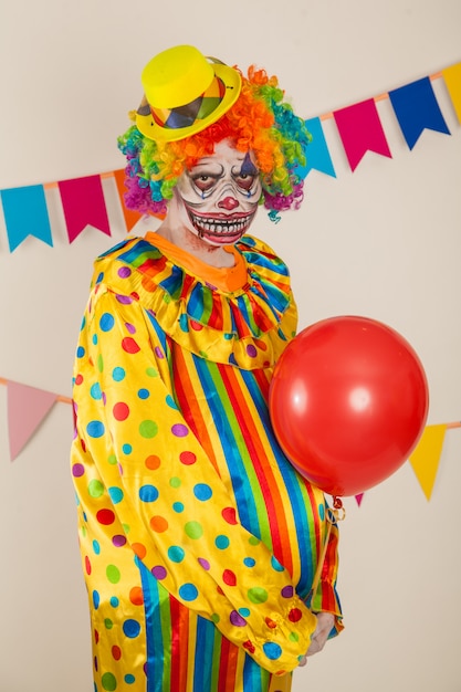 Photo scary clown and red ball. violence and childhood fear