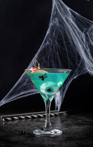 Scary colorful Halloween cocktail with party decorations on dark background with copy space