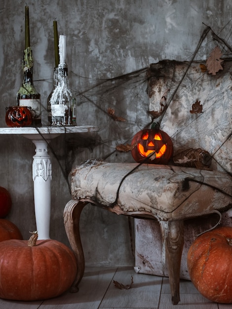 Фото Страшная композиция с тыквой джека и горящими свечами, паутиной и метлой ведьмы на бетонной стене